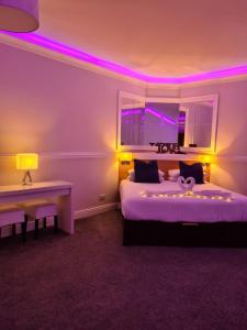 a room with two beds and a desk and purple lights at Caisleain Oir Hotel in Annagry