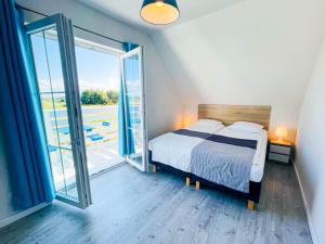 ein Schlafzimmer mit einem Bett und einem großen Fenster in der Unterkunft Domki Summer Home Łeba in Łeba