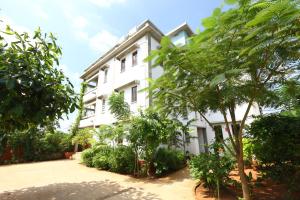un bâtiment blanc avec des arbres devant lui dans l'établissement Hotel Du Palais - Auroville Beach, à Pondichéry