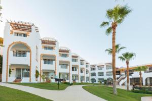 a large white building with palm trees in front of it at Sunrise Remal Resort in Sharm El Sheikh