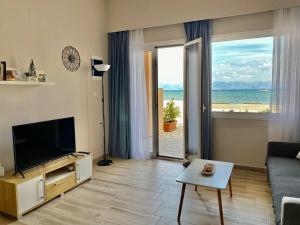 a living room with a television and a view of the ocean at Thalassa in Sidari