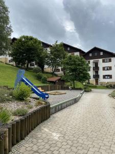 une aire de jeux avec un toboggan bleu en face d'un bâtiment dans l'établissement Ferienwohnung Pitzer, à Missen-Wilhams