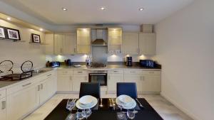 cocina con armarios blancos, mesa y sillas en Orange Apartments Rubislaw Mansions en Aberdeen