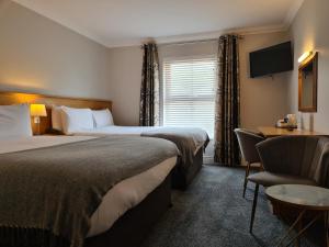 a hotel room with two beds and a desk and a chair at Caisleain Oir Hotel in Annagry