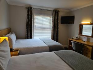 a hotel room with two beds and a desk and a television at Caisleain Oir Hotel in Annagry
