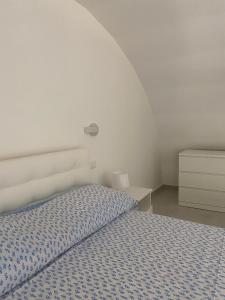 a white bedroom with a bed and a night stand at Zaras 11 in Ischia