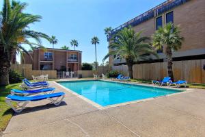 a swimming pool with lounge chairs and a building at Channelview 213 in Port Aransas