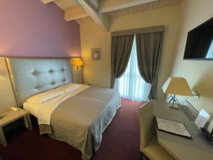 カザレッキオ・ディ・レーノにあるBoutique Hotel Calzavecchioのベッドとデスクが備わるホテルルームです。