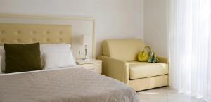 a bedroom with a bed and a yellow chair at Residence Suite Smeraldo in Riccione