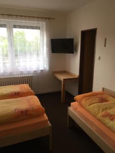 a room with three beds and a tv and a window at Pokoje RELAX in Rybniště