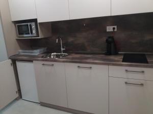 eine Küche mit weißen Schränken, einer Spüle und einer Mikrowelle in der Unterkunft Студио Булаир 1 in Burgas City