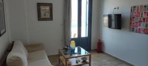 a living room with a white couch and a table at Asvestoti maisonettes Blue house in Astypalaia