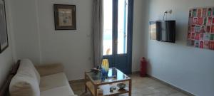 a living room with a white couch and a table at Asvestoti maisonettes Blue house in Astypalaia Town