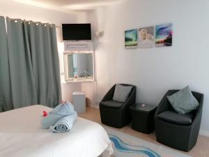 a bedroom with a bed and two chairs and a tv at Marisa Residences in La Gaulette