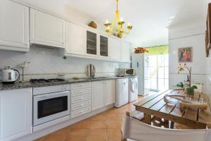 cocina con armarios blancos y mesa de madera en Casa da Praia, en Albufeira