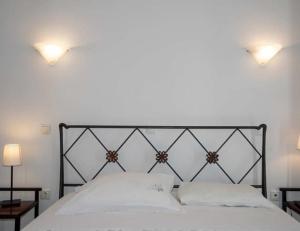 a white bed with two lights on top of it at Asvestoti maisonettes Blue house in Astypalaia