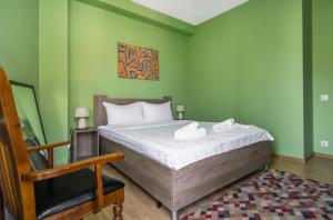 a bedroom with a bed with green walls and a chair at Hotel "Elesa Wera" in Tbilisi City