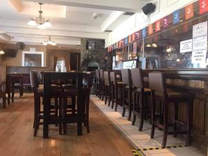 a restaurant with black chairs and a bar at Caisleain Oir Hotel in Annagry