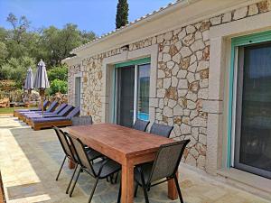 una mesa de madera y sillas en un patio en Villa di pietra, en Liapades