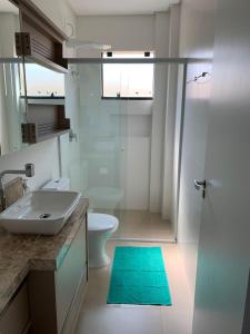 a bathroom with a sink and a toilet and a shower at Lindo Apartamento no Mariscal, Bombinhas, com estacionamento e quintal, a 290 metros da praia do Canto Grande!!! in Bombinhas
