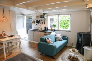 a living room with a blue couch and a kitchen at Morning Glory in Wemeldinge