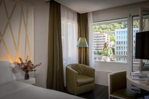 ルガノにあるホテル アドミラル ルガノのベッド1台、椅子、窓が備わる客室です。