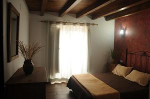 a bedroom with a bed and a window with a vase at EL VASALLO in Tragacete