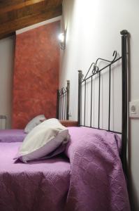 a bed with purple sheets and pillows on it at EL VASALLO in Tragacete