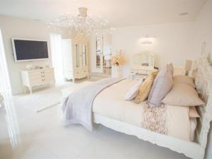 a white bedroom with a large bed and a television at Queen Bee & B in Merthyr Tydfil