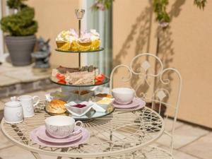 a table with a tray of pastries and cups on it at Queen Bee & B in Merthyr Tydfil