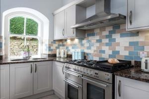 a kitchen with white cabinets and a stove top oven at Eisteddfa in Criccieth