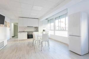 a white kitchen with a table and white appliances at Apartamentos Arena y Cairo in Murcia