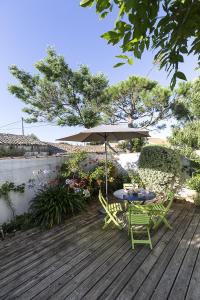 a table and chairs with an umbrella on a deck at 350m de la mer - maison pour 6 in L'Ile d'Yeu