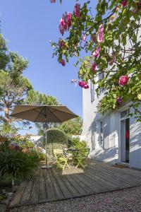 a wooden deck with a table and an umbrella at 350m de la mer - maison pour 6 in L'Ile d'Yeu +16 photos