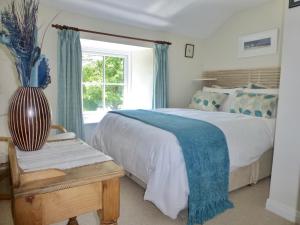 a bedroom with a large bed and a vase on a table at Tresowes Green Cottage in Helston