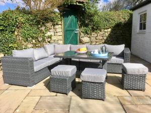 a patio with a couch and a table and stools at Tresowes Green Cottage in Helston