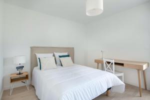 um quarto com uma cama branca e uma secretária em Bel appartement pour 6 personnes avec balcon en bord de mer em Pléneuf-Val-André