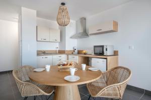 cocina con mesa de madera y sillas en Un bel appartement avec vue sur le large a Pleneuf-Val-Andre, en Pléneuf-Val-André
