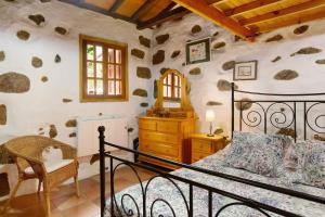 1 dormitorio con 1 cama en una habitación con rocas en la pared en Casa Los Pinos, en Agüimes