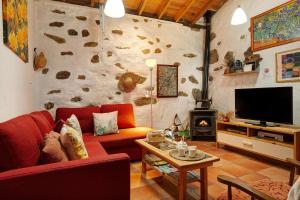 Una sala de estar con un sofá rojo y un televisor. en Casa Los Pinos, en Agüimes