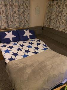 Una cama con estrellas azules y blancas. en KellysHolidayHomes Atlas 3 bedrooms caravan, en Weeley