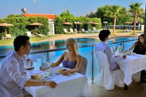 阿凡多的住宿－阿凡灣度假套房酒店，一群坐在游泳池前桌边的人