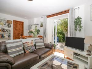 ein Wohnzimmer mit Sofa und Fernseher in der Unterkunft Mackerel Cottage in Budleigh Salterton