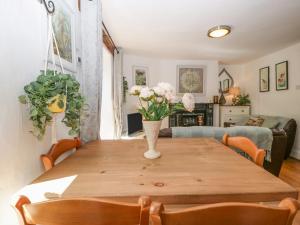 a dining room table with a vase of flowers on it at Mackerel Cottage in Budleigh Salterton