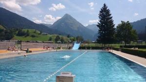 a swimming pool with a waterfall and people in it at Blue Note Apartments in Schoppernau