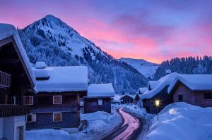 ein schneebedecktes Dorf mit Bergen im Hintergrund in der Unterkunft Blue Note Apartments in Schoppernau
