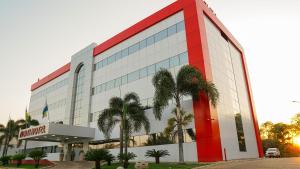 a red and white building with palm trees in front of it at Oiti Hotel - Gurupi in Gurupi