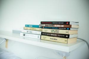 a stack of books sitting on a white shelf at Osada Solasu in Złoty Stok