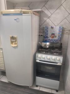 uma pequena cozinha com um frigorífico e um fogão em Casa 50 mts da praia Caravelas PR com ventiladores em Matinhos