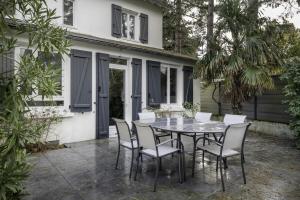 een patio met een tafel en stoelen voor een huis bij Villa Les Libellules pour 8 à 9 personnes in La Baule